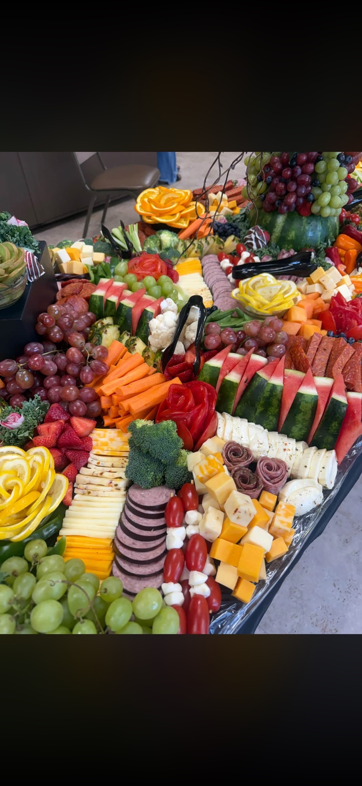 Charcuterie display with cheeses, sliced meats, grapes, watermelon and vegetables